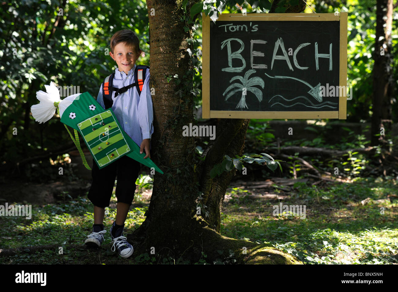 Première journée à l'école. Garçon avec cône en carton dans la cour de l'école. Banque D'Images