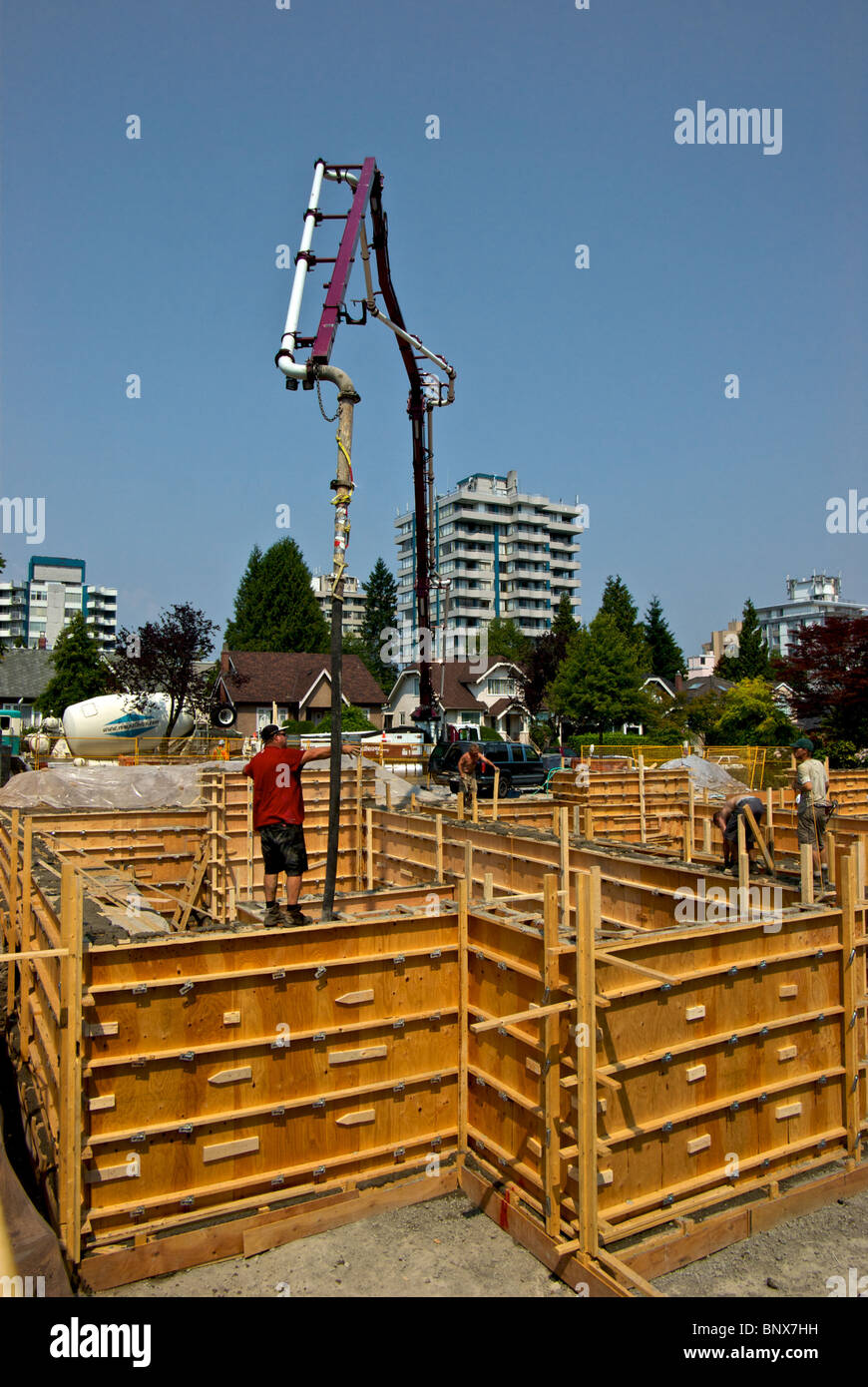 Camion-pompe béton utilise très grands tuyau de flèche hydraulique pour atteindre les formes de fondation de contreplaqué à Vancouver house construction site Banque D'Images