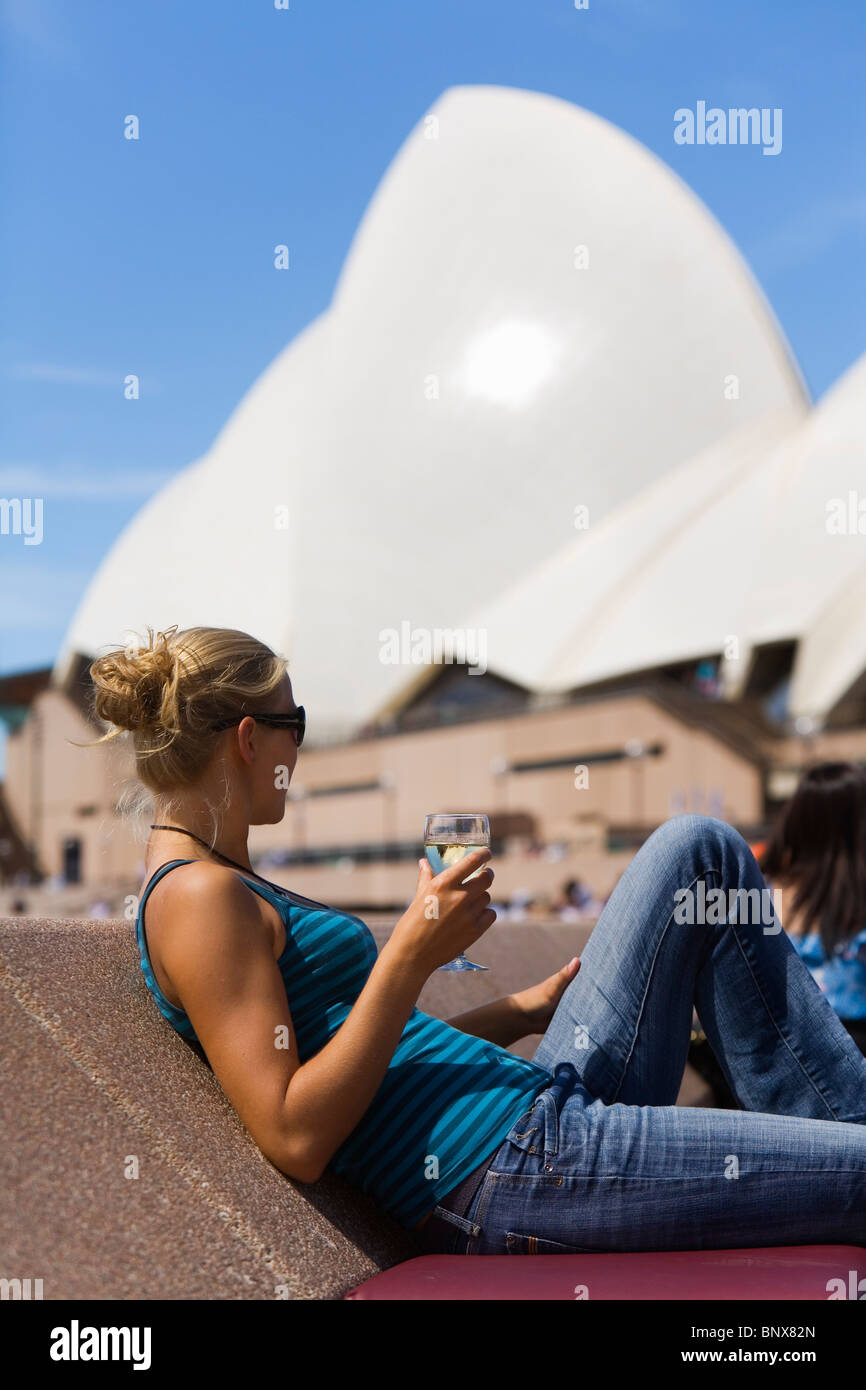 Une femme bénéficie d'un verre de vin au bar de l'opéra à l'Opéra en arrière-plan. Sydney, Nouvelle-Galles du Sud, Australie. Banque D'Images