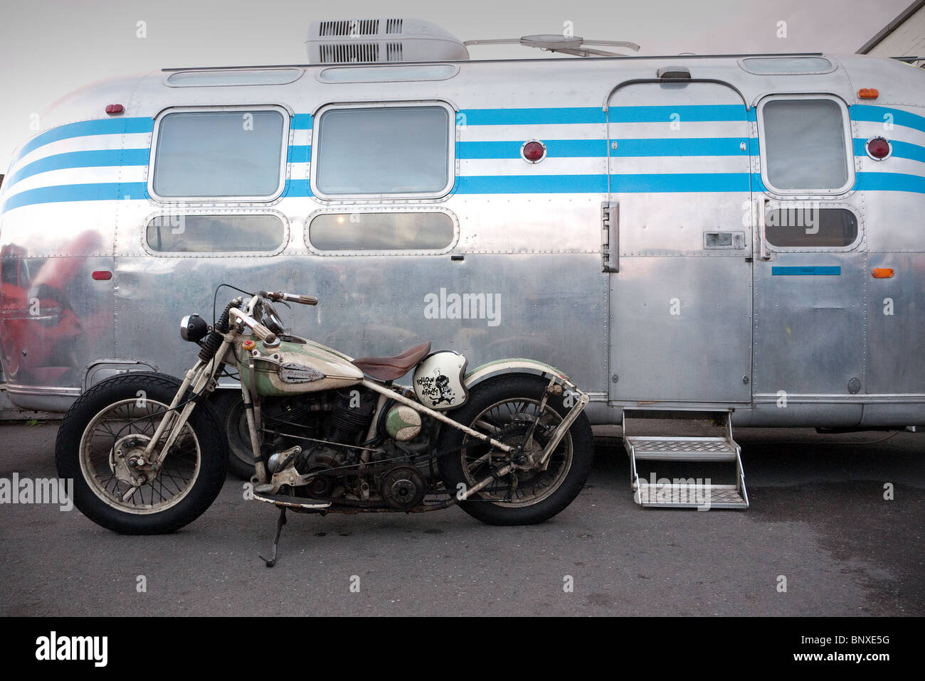 Vieille moto Harley Davidson parqué par une caravane Airstream Ace Cafe London UK Banque D'Images