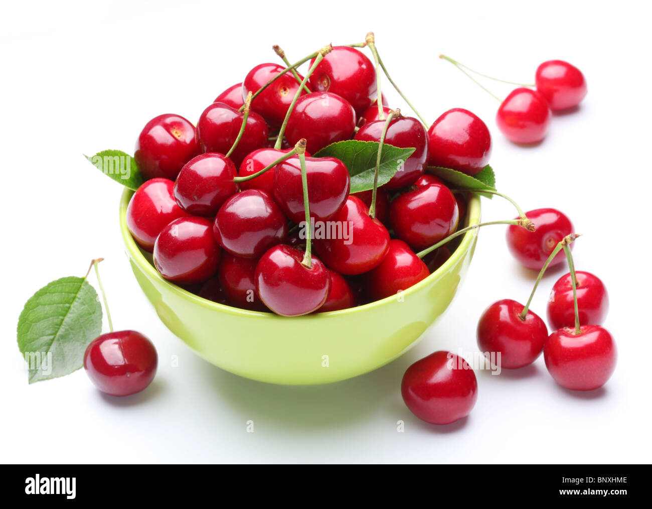 Bol avec les cerises mûres et quelques cerises près de la cuvette. Isolé sur un fond blanc. Banque D'Images