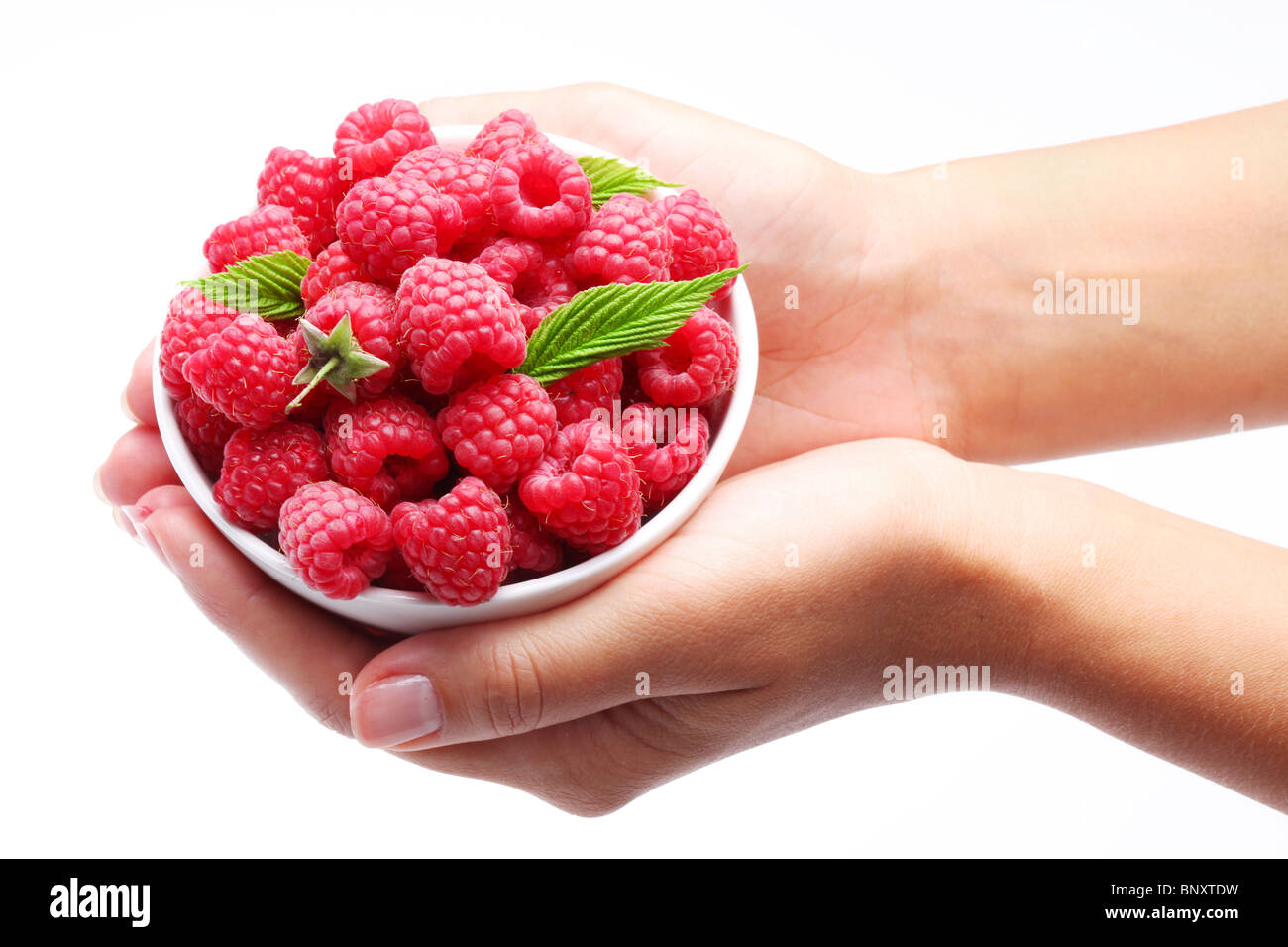 De la vaisselle avec des framboises dans femme mains. Isolé sur un fond blanc. Banque D'Images