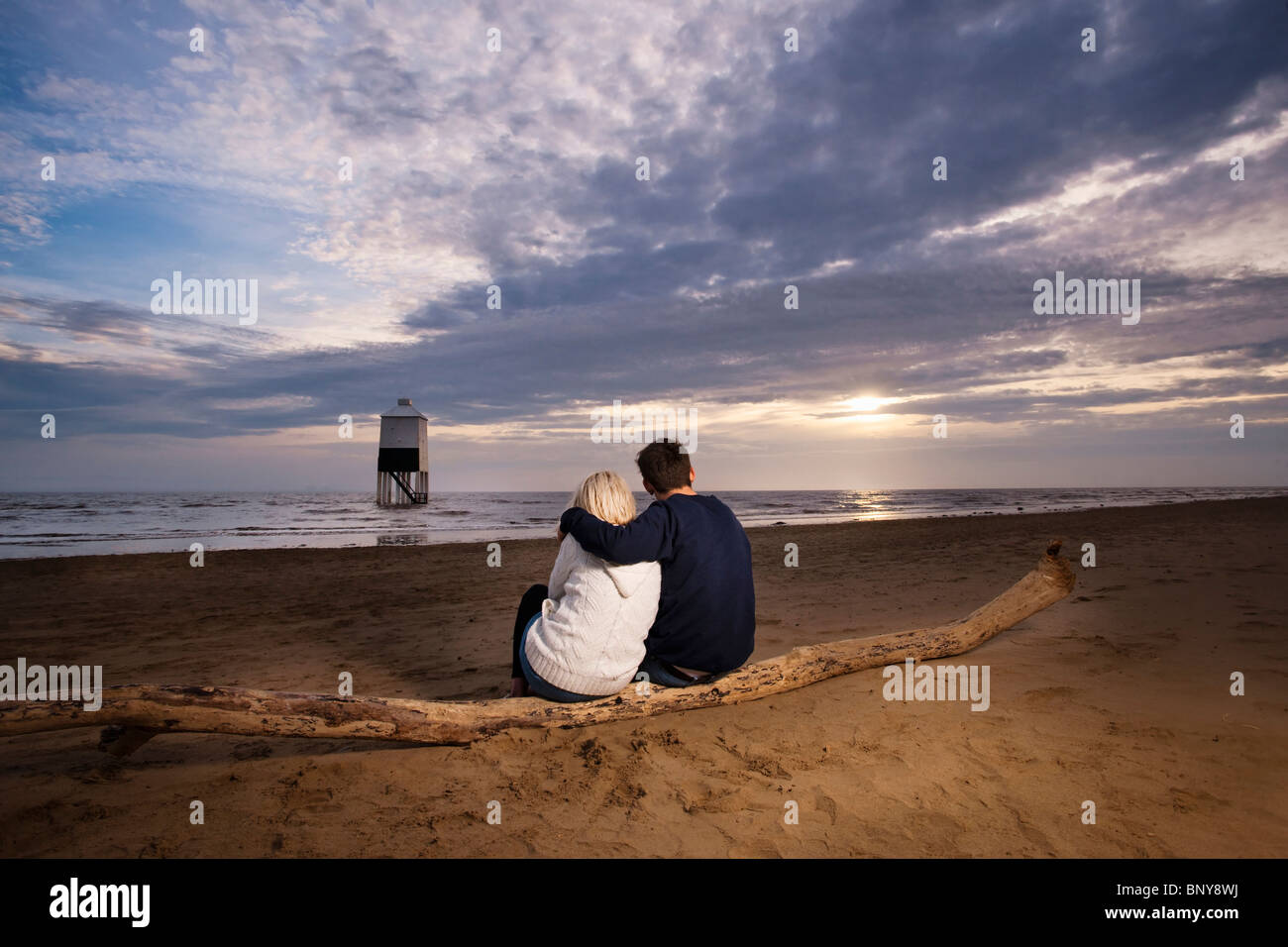 Couple regardant le coucher du soleil sur la plage Banque D'Images