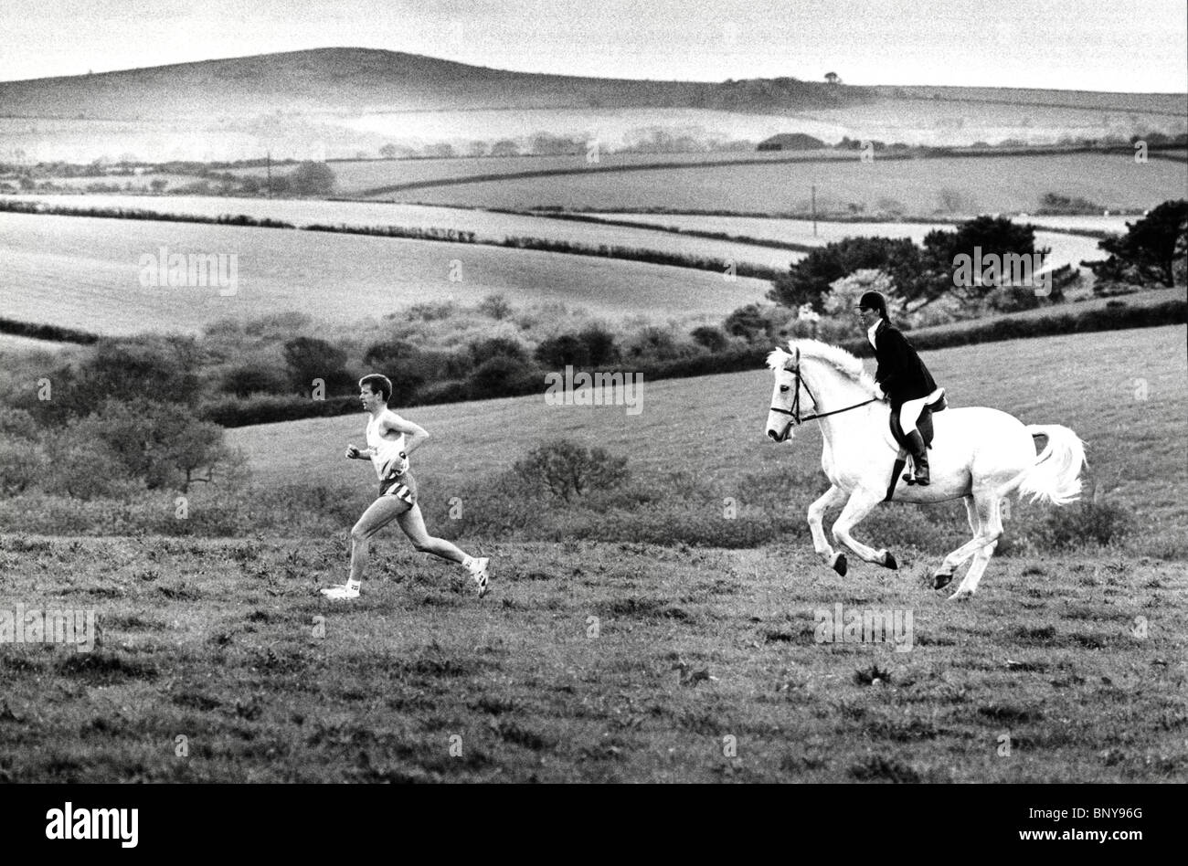 Homme qui court dans le champ avec une femme à cheval pas loin derrière. Banque D'Images