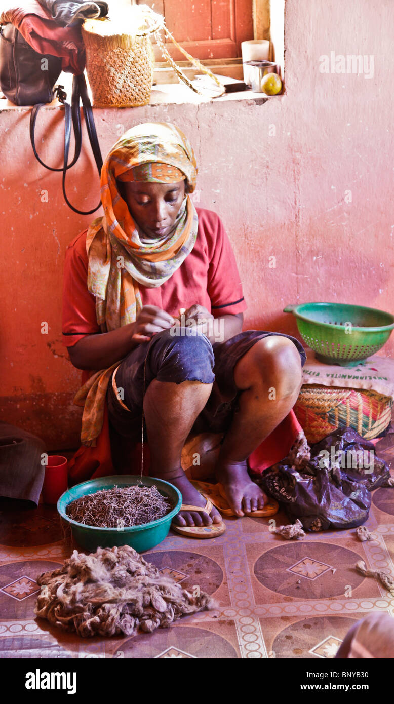Femme Malgache en fil de soie en le frottant sur sa cuisse, Antemoro, usine de soie dans le sud-est de Madagascar Banque D'Images