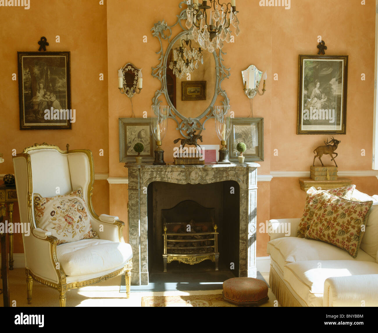 Aile crème-chaise et canapé de chaque côté de la cheminée de marbre orné miroir antique ci-dessous sur le mur de la salle de séjour Banque D'Images