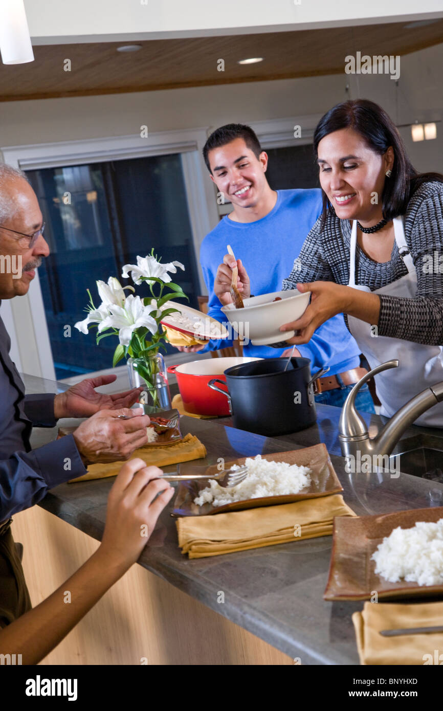 Mère hispanique servant des repas maison dans la cuisine de la famille Banque D'Images