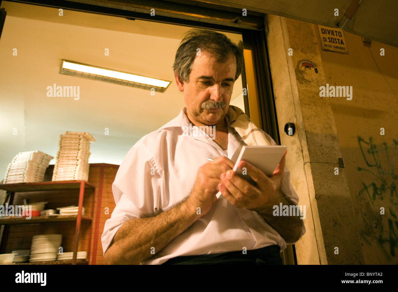 Garçon avec un ordinateur portable devant une pizzeria, Rome, Italie Banque D'Images