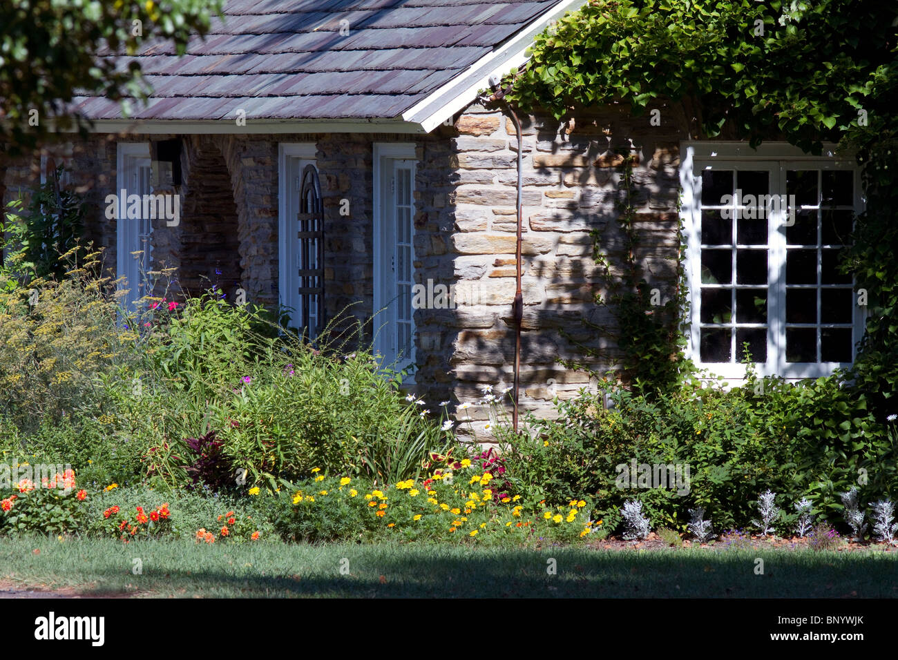 Coin d'une maison en pierre avec un lit de fleurs d'été. Banque D'Images