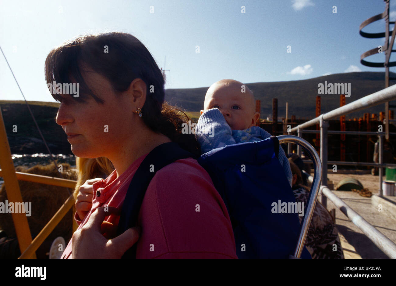 Foula les Shetland Ecosse mère exerçant son bébé sur son dos en attendant le bateau et l'offre de courrier hebdomadaire Banque D'Images