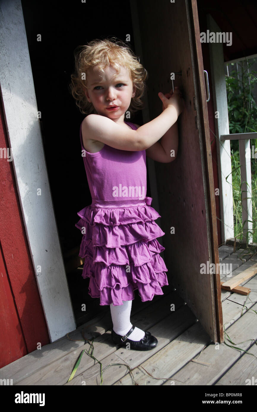 Petite fille vêtements enfant en partie à l'extérieur de l'ouverture d'un  modèle de porte en bois playhouse publié Photo Stock - Alamy