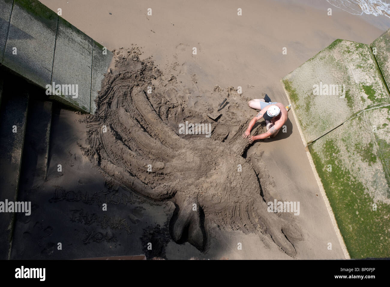 Un artiste de rue, la création d'une sculpture de sable d'un crabe sur la Thames, London Beach Banque D'Images