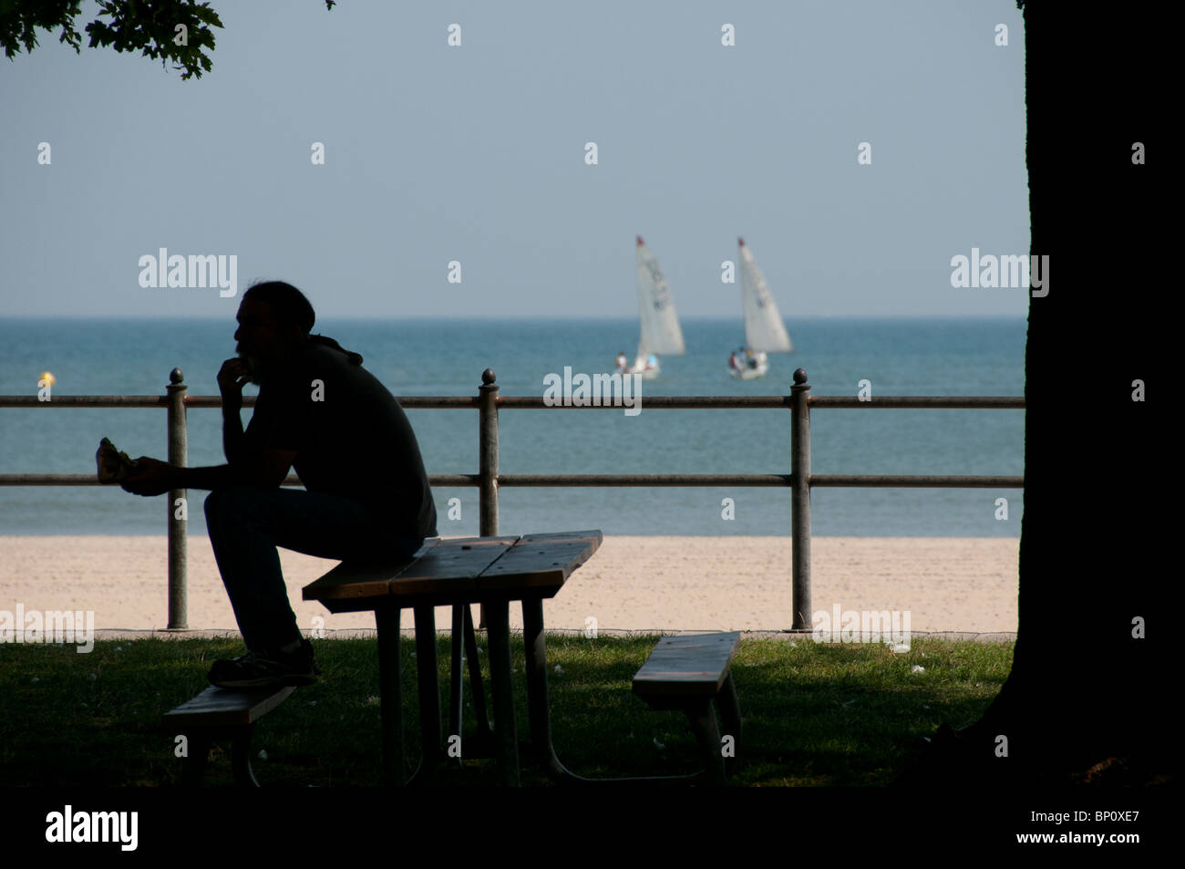 Homme assis sur le banc de parc à Ontario Beach. Banque D'Images