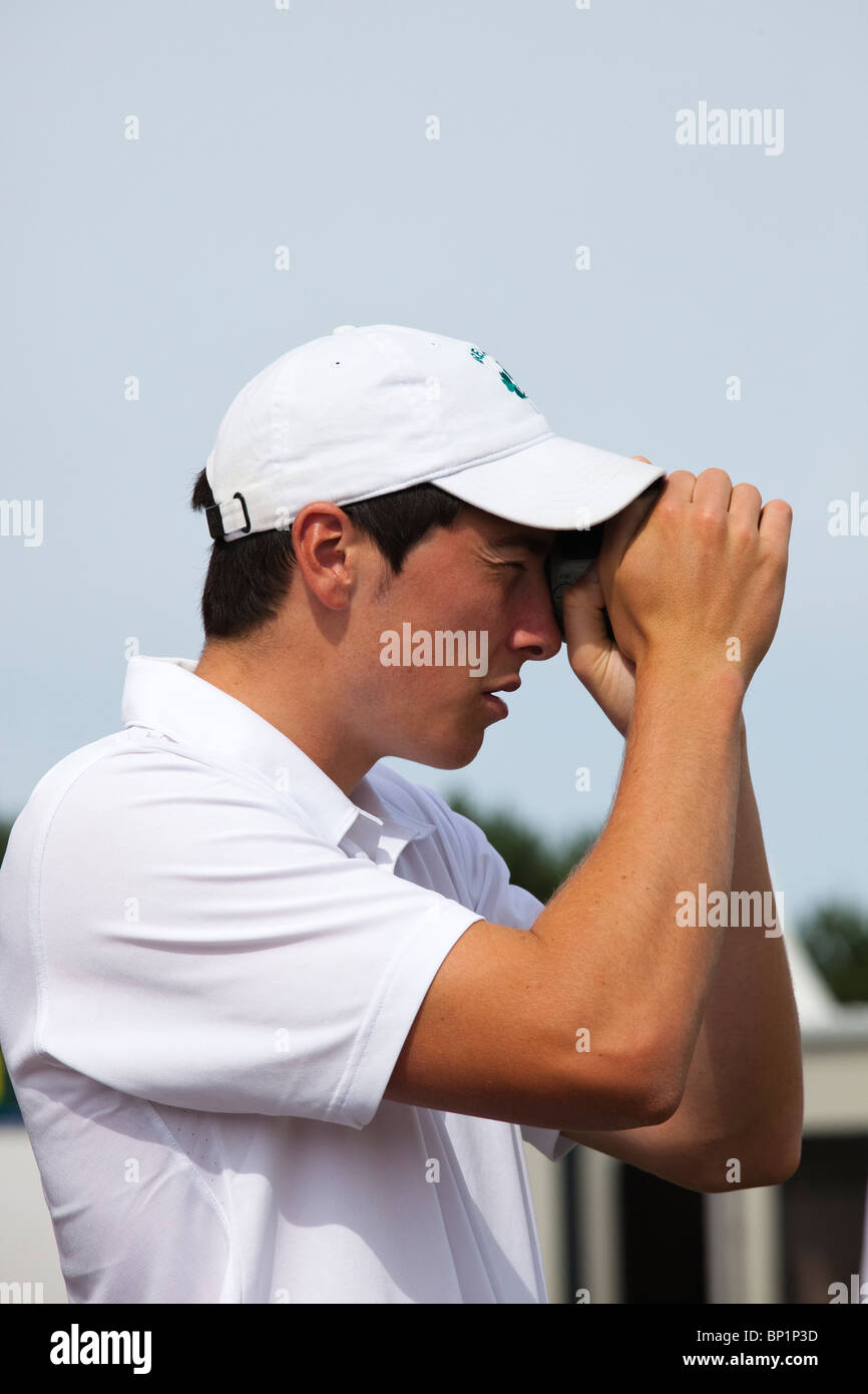 Jeune golfeur à l'aide d'un appareil de mesure de distance sur un terrain de golf. Banque D'Images
