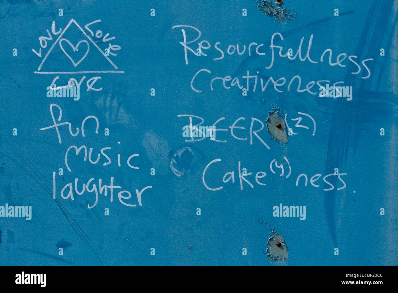 Amusant graffitis sur un mur bleu vantant l'amour fun music et le rire. Et de la bière. Tous nous avons besoin d'un monde meilleur. Banque D'Images