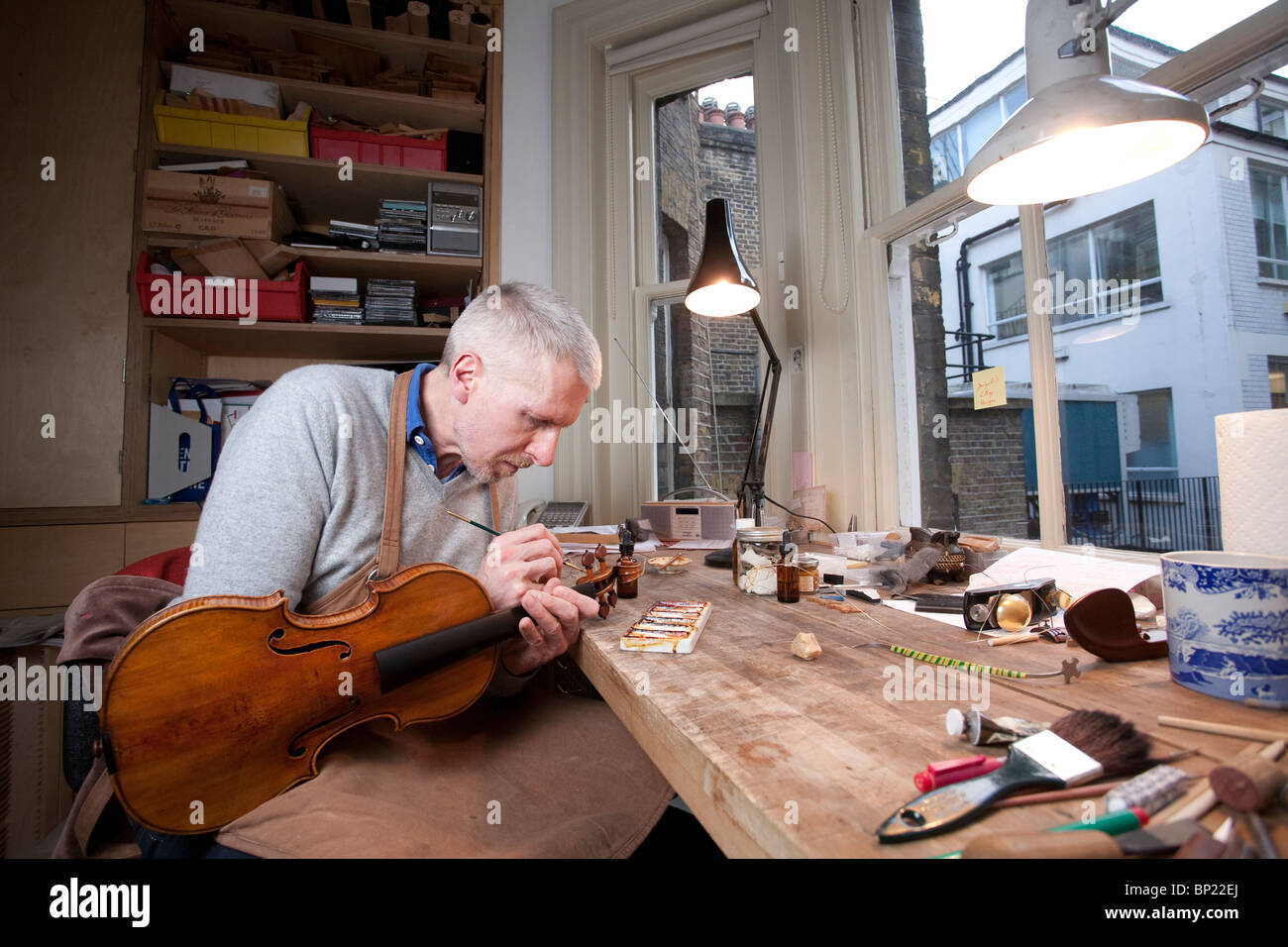 Un restaurateur de violon classique sur un instrument de travail dans son atelier, Londres, Royaume-Uni. Photo:Jeff Gilbert Banque D'Images