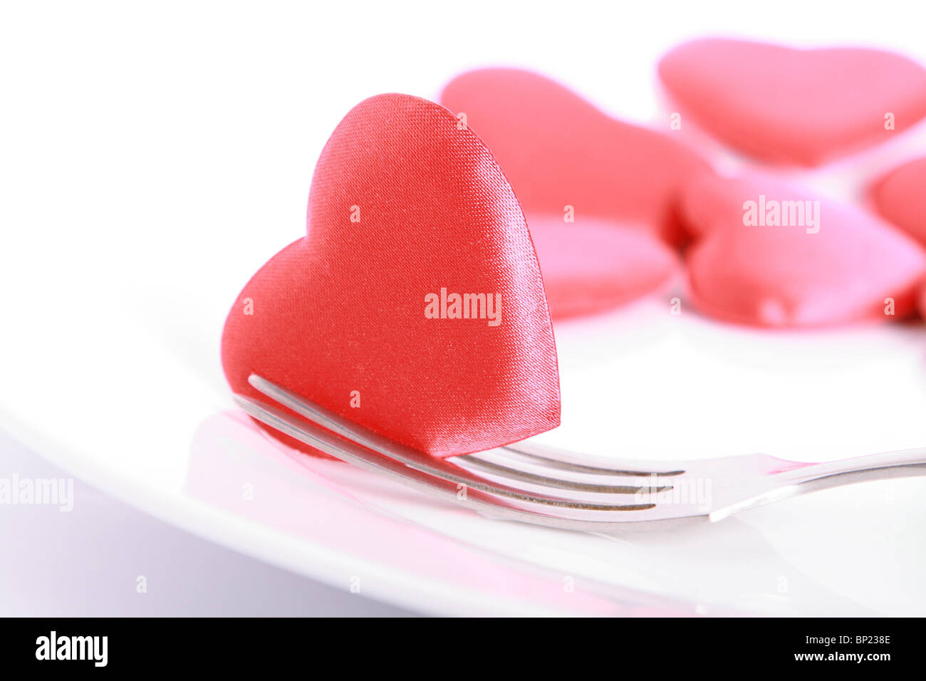 Coeur rouge percé de fourchette sur l'assiette Banque D'Images