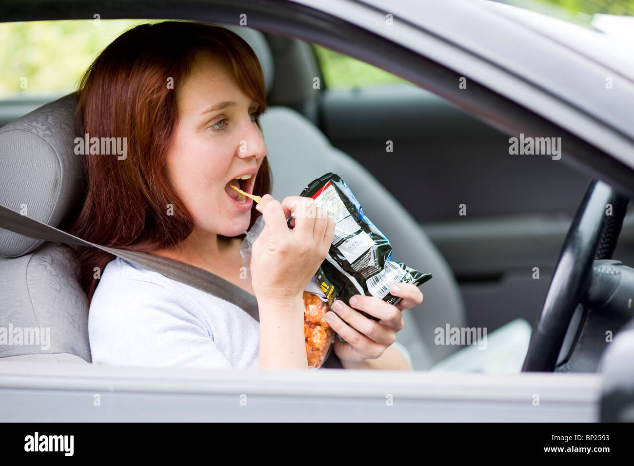 Pendant la conduite de snacking Femme Banque D'Images