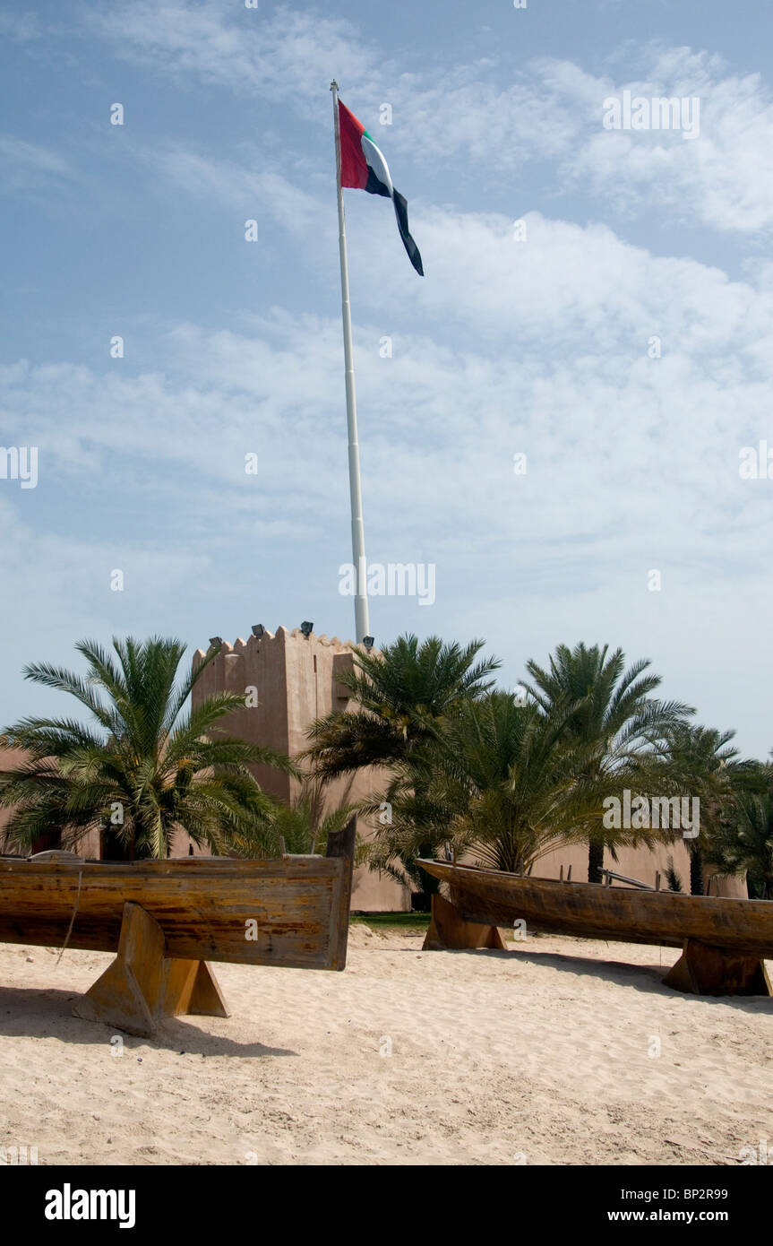 Forteresse en pisé avec flag flying et échoués sur les bateaux traditionnels, à l'Heritage Village, Abu Dhabi Banque D'Images