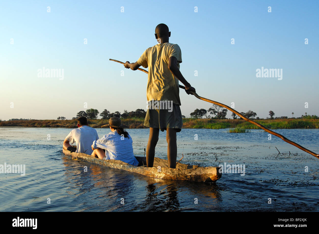 Poler auprès des touristes dans un logboat mokoro sur excursion dans l'Okavango Delta, Botswana Banque D'Images