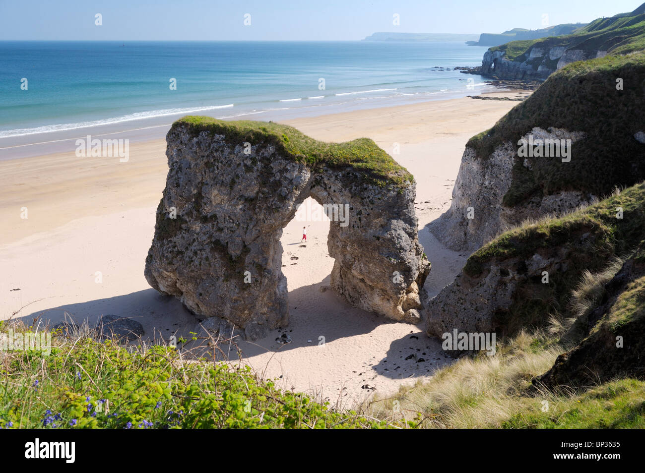 Jeune femme marche sur plage déserte au White Rocks entre Portrush et Bushmills, Irlande du Nord. Falaises de calcaire érodé Banque D'Images