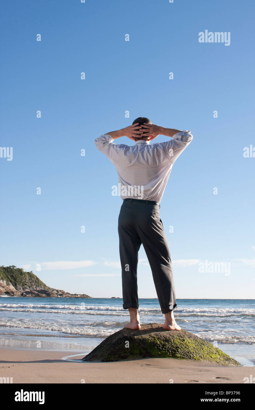 Businessman standing pieds nus sur un rocher au bord de la mer Banque D'Images