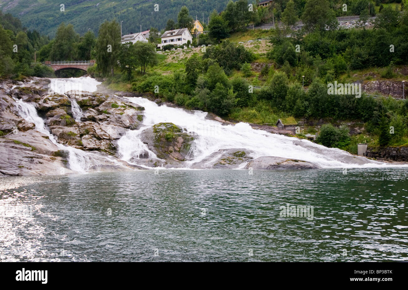 La cascade à travers Hellesylt, Norvège, Stranda, un petit port de ferries touristiques donnant accès au fjord de Geiranger. Banque D'Images
