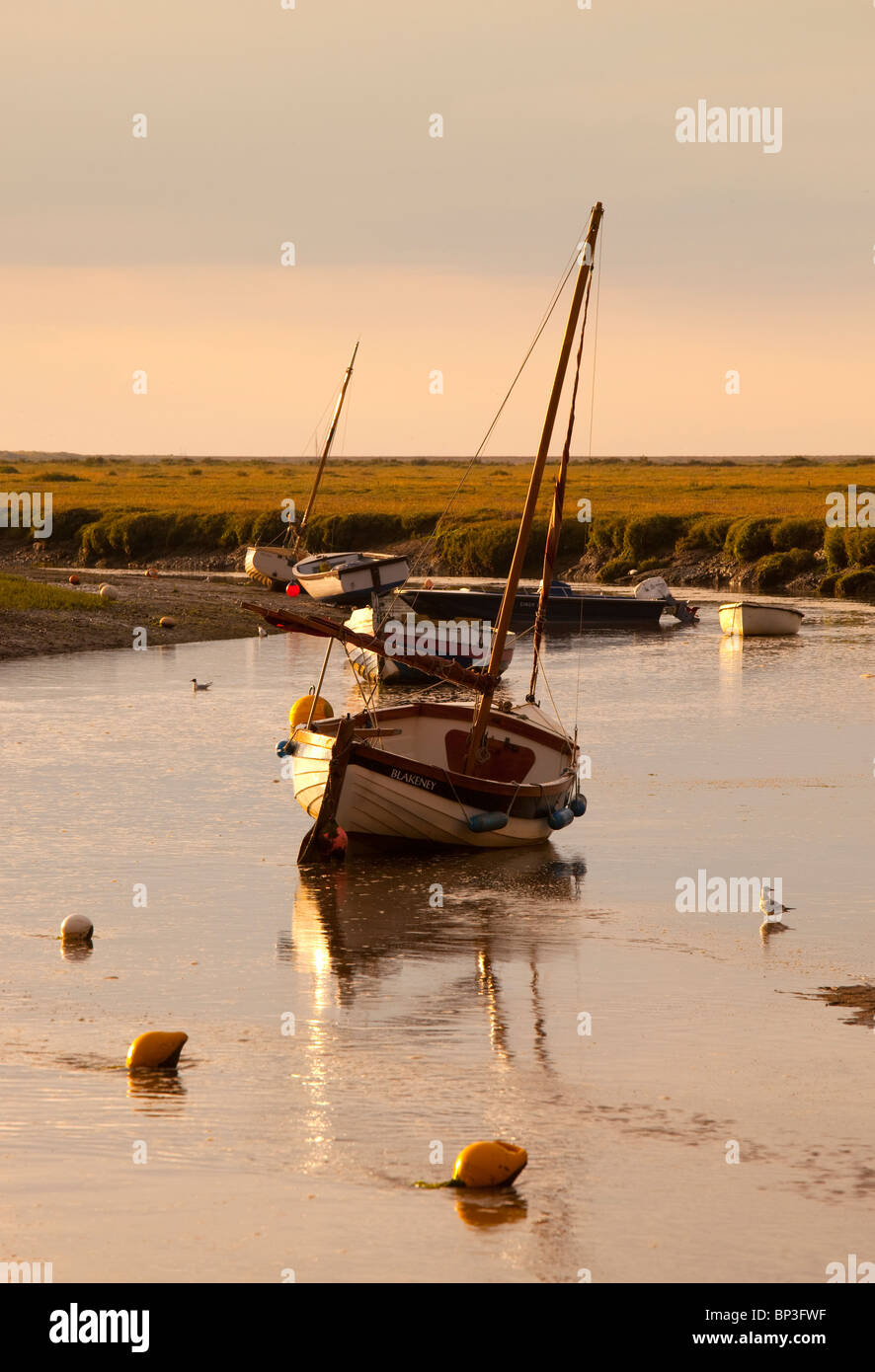 Bateaux dans canal comme marée se retire en fin d'après-midi à Blakeney, Norfolk, Angleterre Banque D'Images