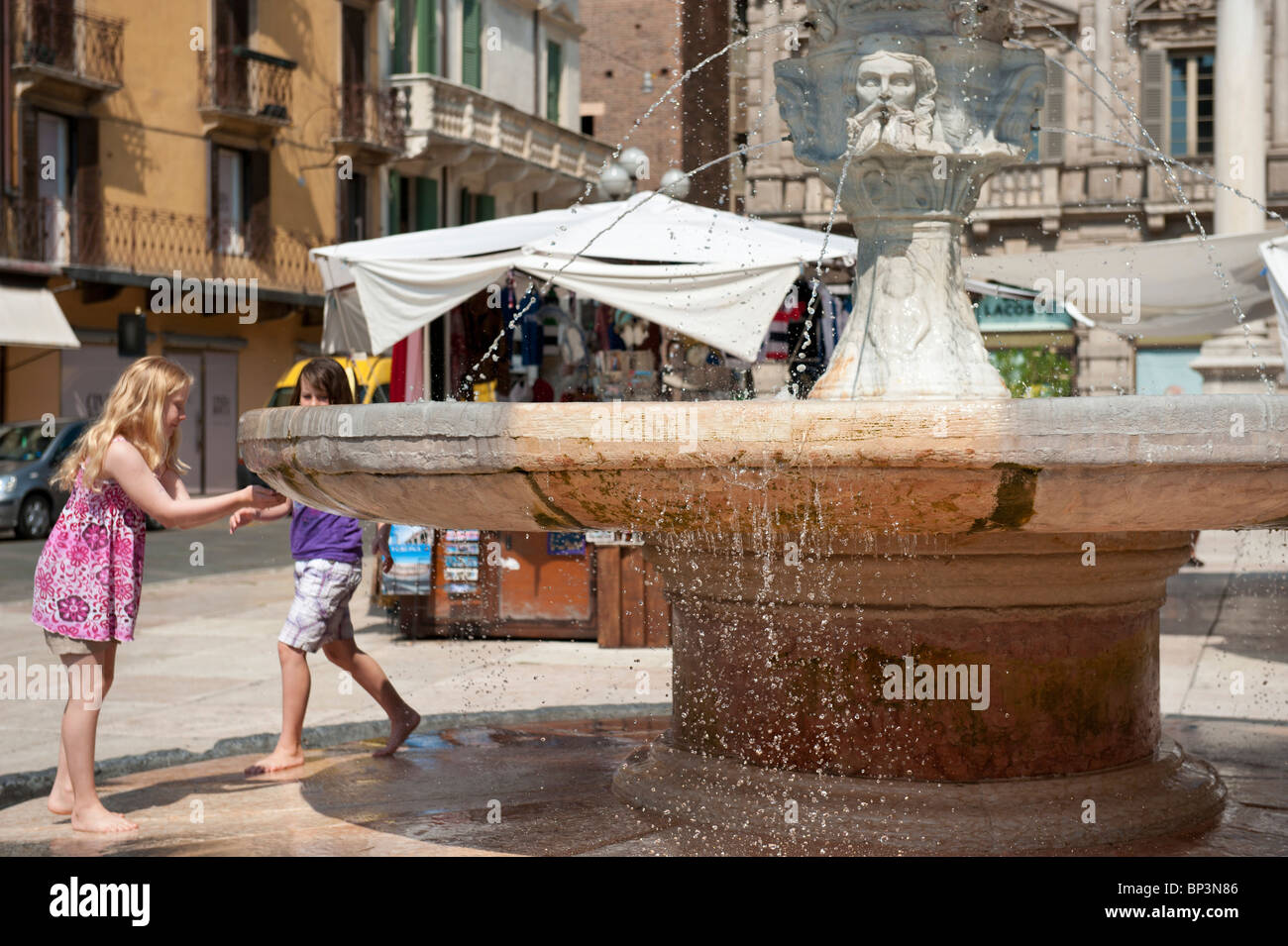 Deux filles jouent dans il Fontana di Madonna Verona Piazza Erbe Verona Italie Banque D'Images