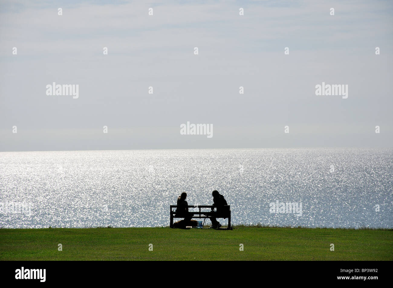 Couple assis sur un banc, l', Greensward Frinton and-on-Sea, Essex, Angleterre, Royaume-Uni Banque D'Images