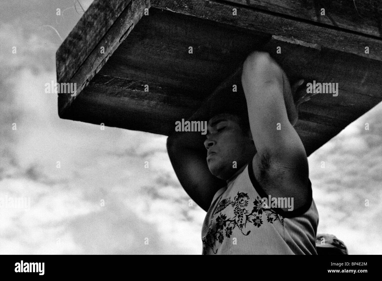 Un jeune homme portant une grande boîte remplie de poissons sur sa tête dans le port de Belém, Brésil. Banque D'Images