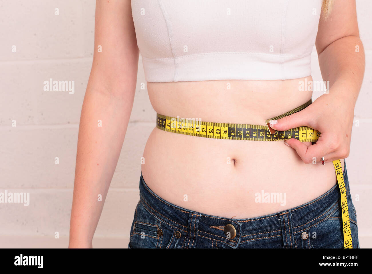 2010 juillet - Jeune femme mesurant sa taille de bordure Banque D'Images