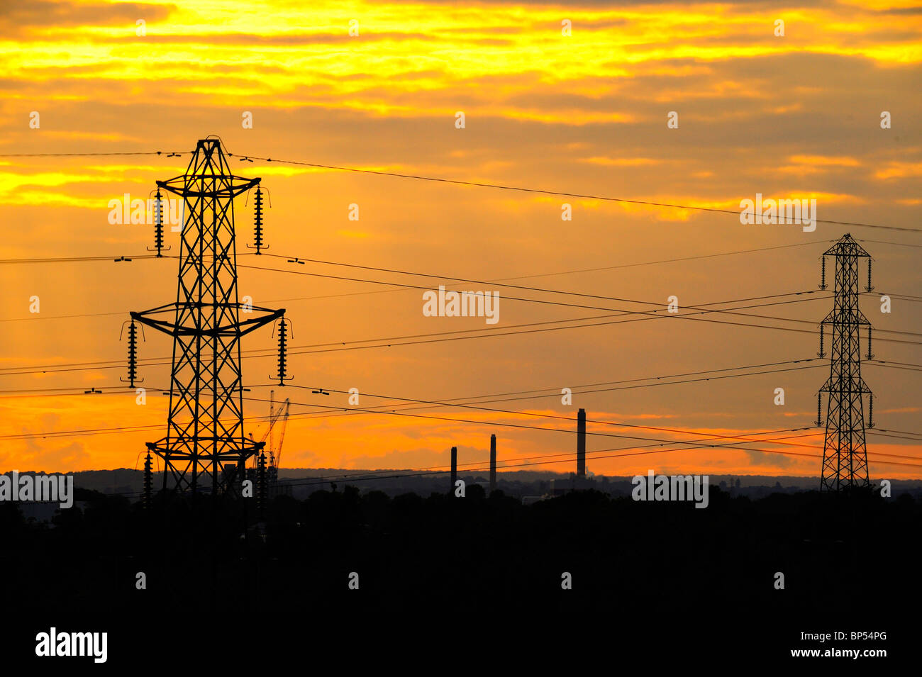 Coucher du soleil, le paysage industriel avec des pylônes électriques et cheminées Banque D'Images