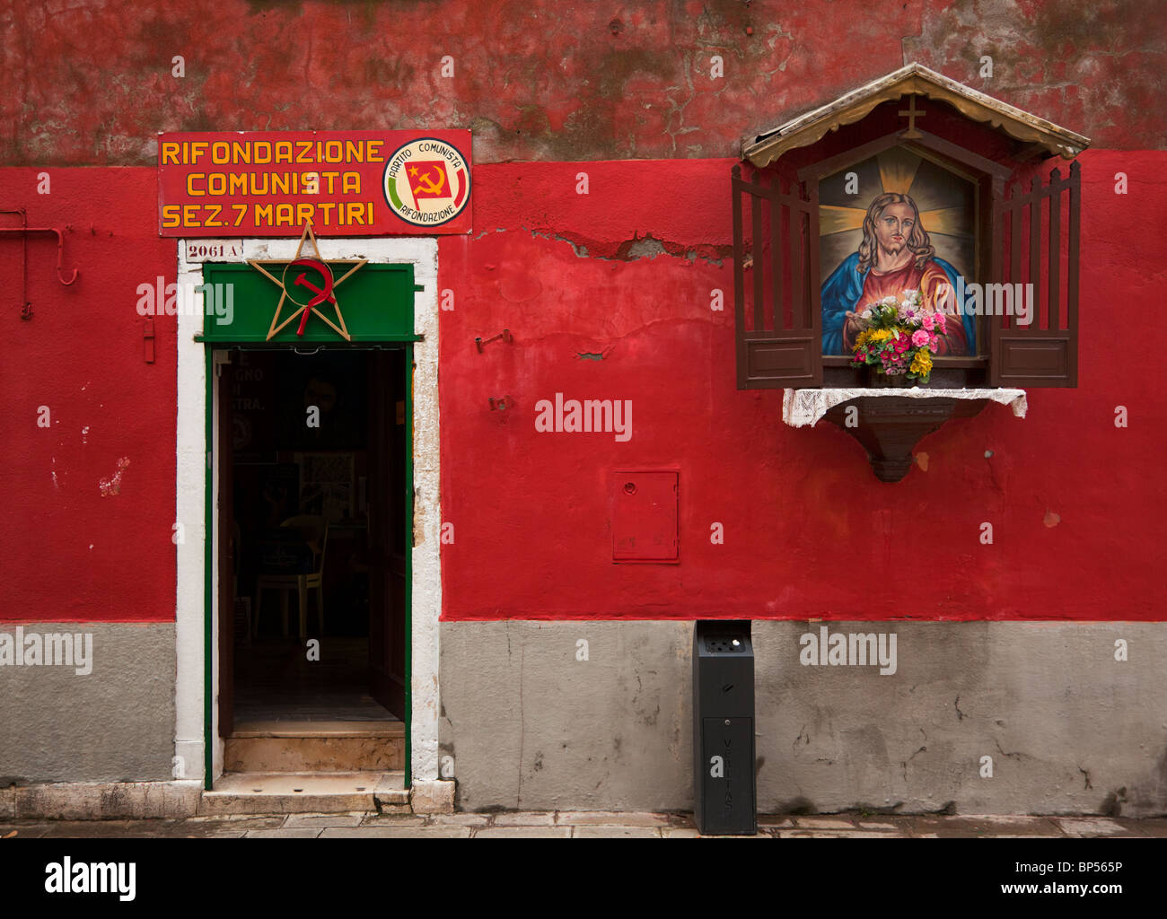 Entrée du bureau du parti communiste à Venise, lieu de culte avec la peinture de Jésus accroché au mur rouge à côté de la porte Banque D'Images