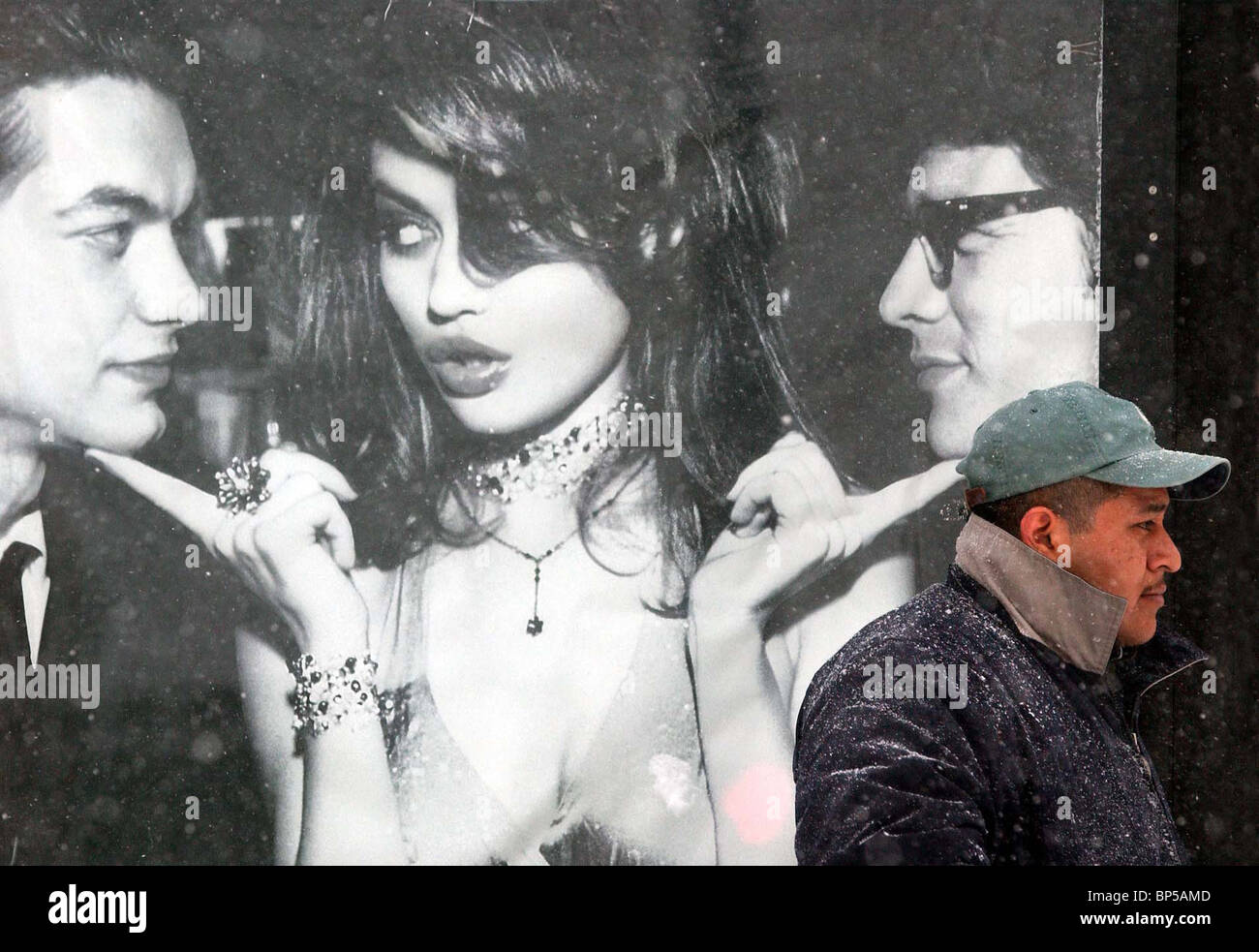 Une scène de rue surréaliste comme un homme passe par une grande fenêtre annonce dans une tempête de neige. La photographie de rue Banque D'Images