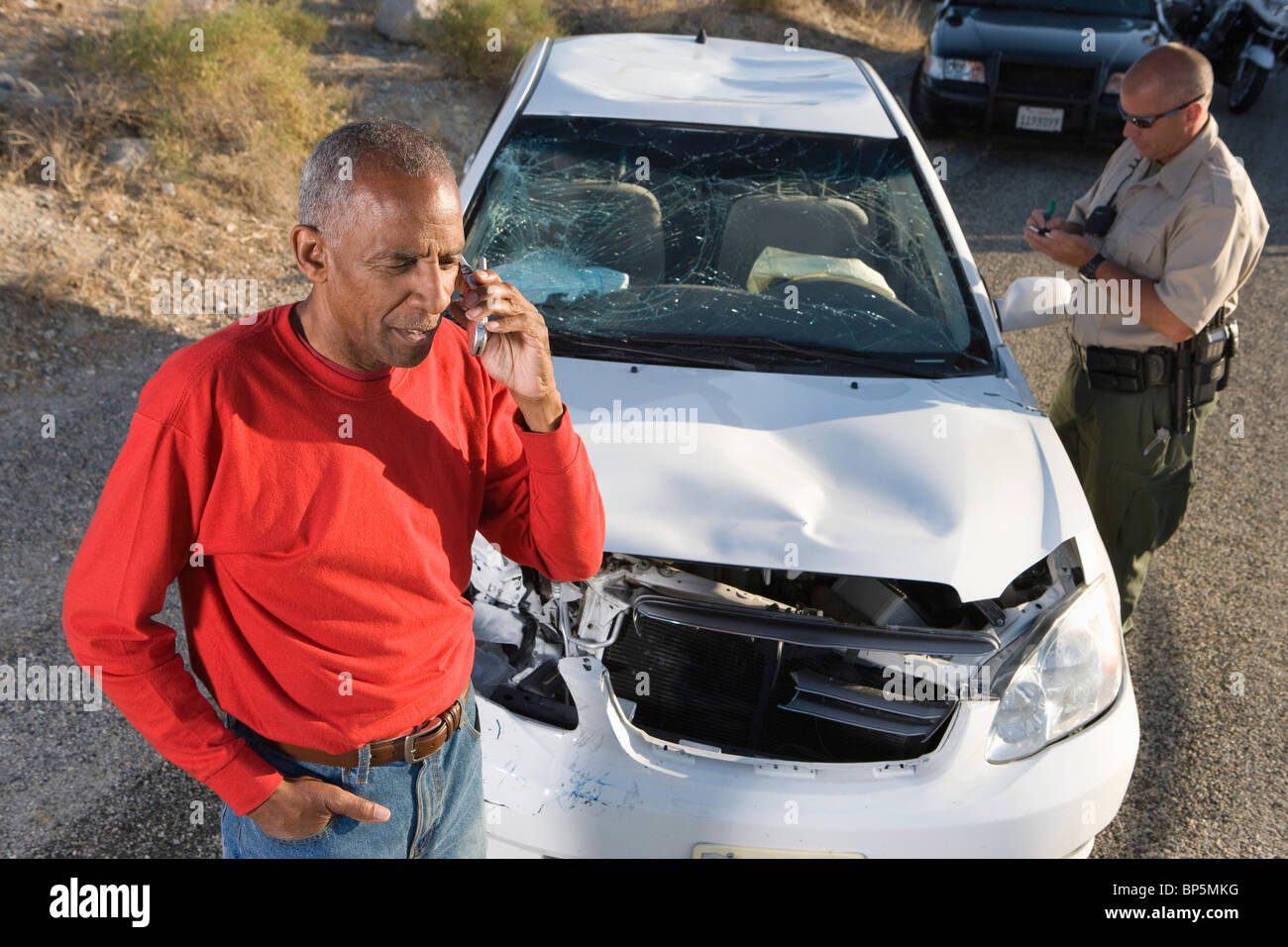 Homme avec un policier sur téléphone mobile suite à accident de voiture Banque D'Images