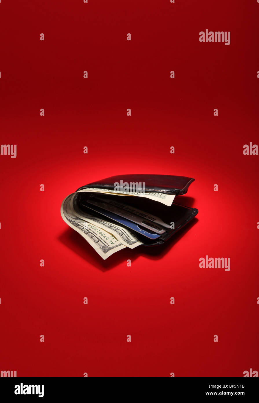 Un portefeuille en cuir noir avec de l'argent sur un fond rouge vif, un bureau est de 300 dollars Banque D'Images