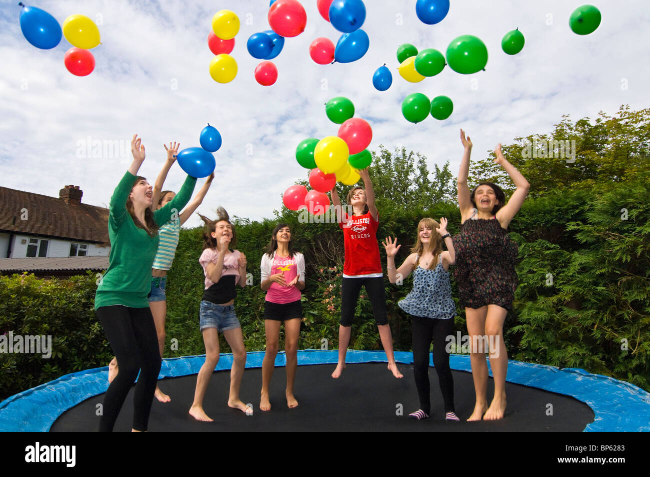 Close up portrait of horizontal d'un groupe d'amies avec des ballons colorés de sauter sur un trampoline dans un jardin Banque D'Images