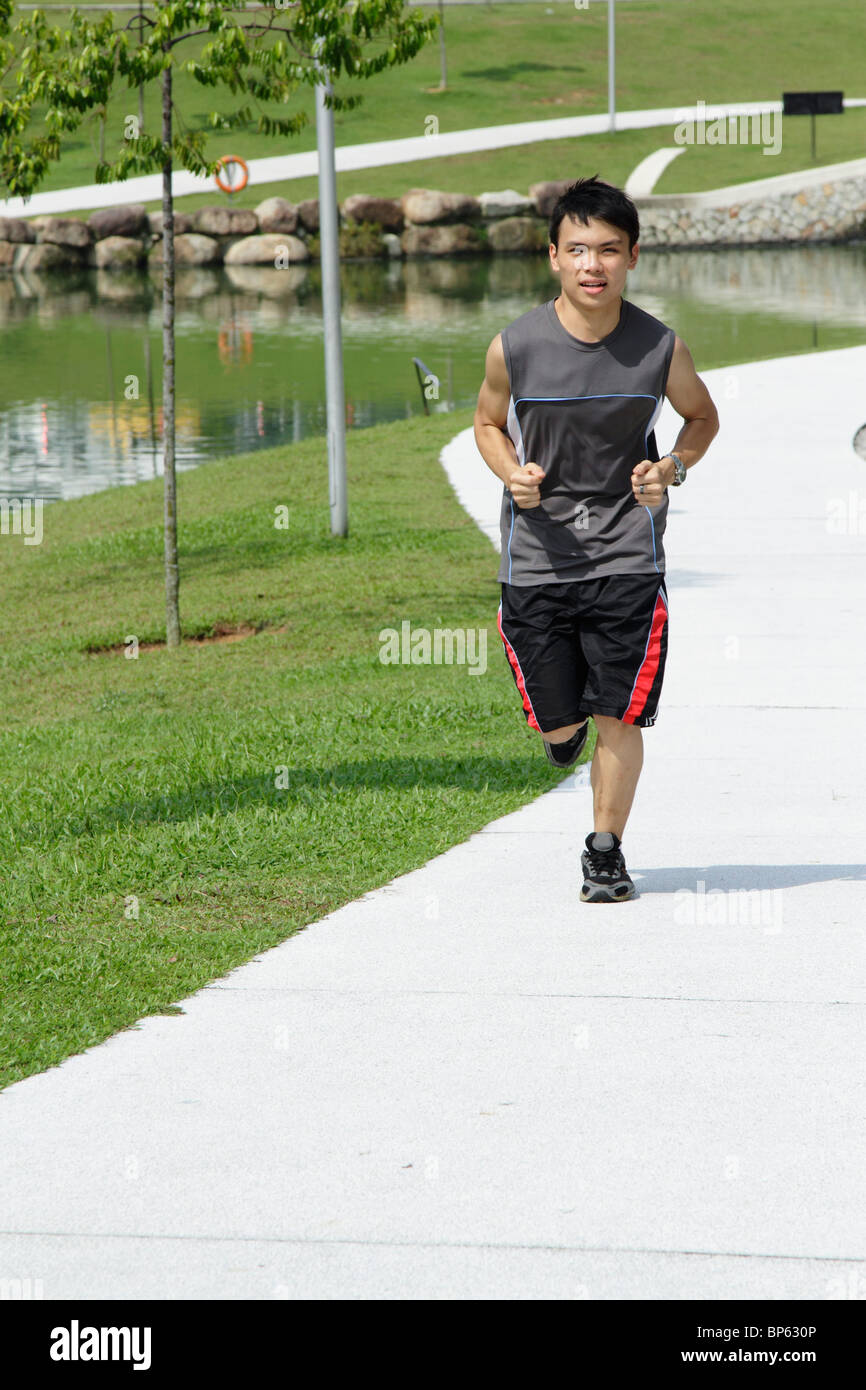 Un jeune homme jogging à un parc Banque D'Images