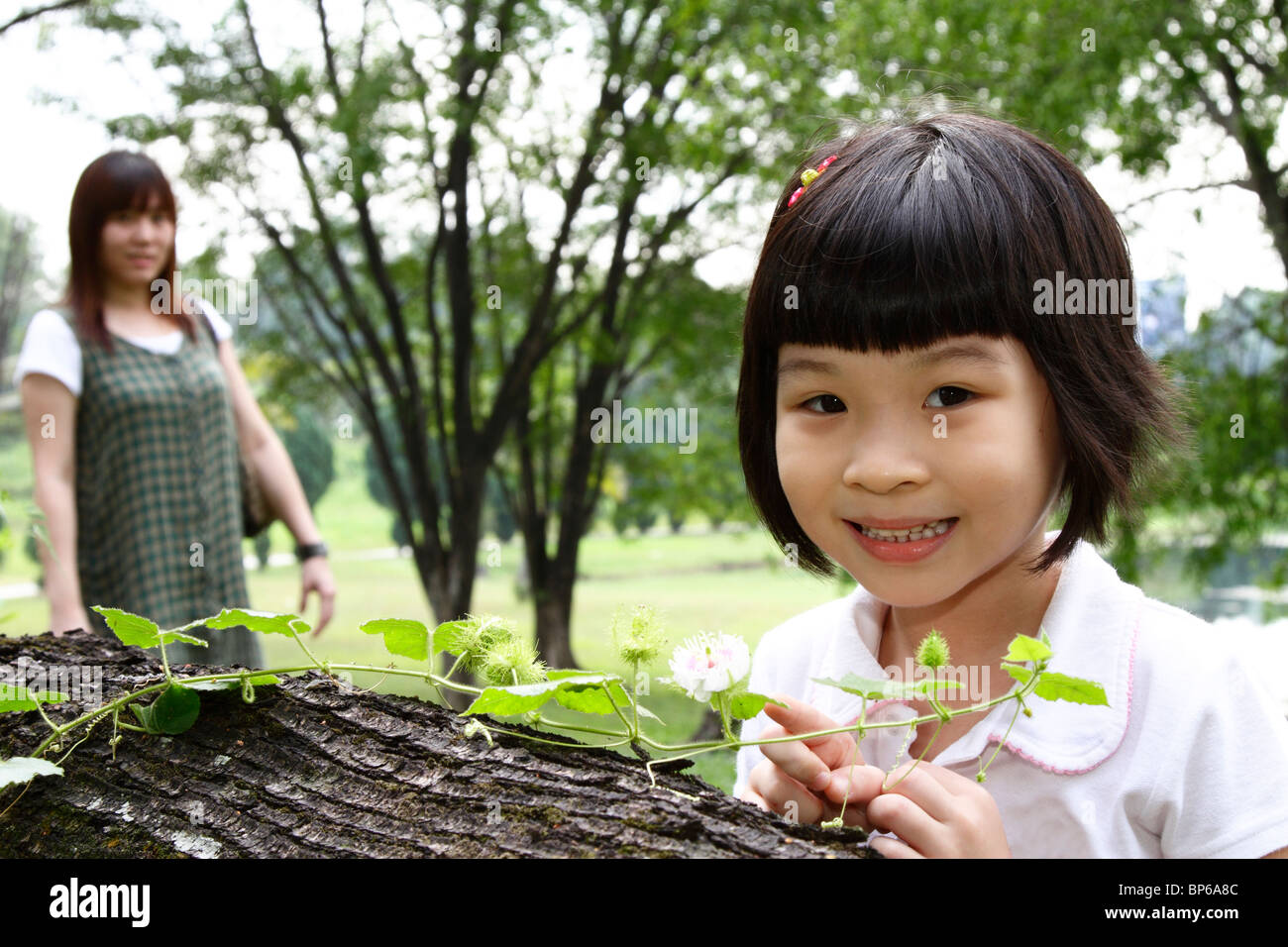 Une fille asiatique curieux l'examen d'une plante rampante que sa mère watches Banque D'Images