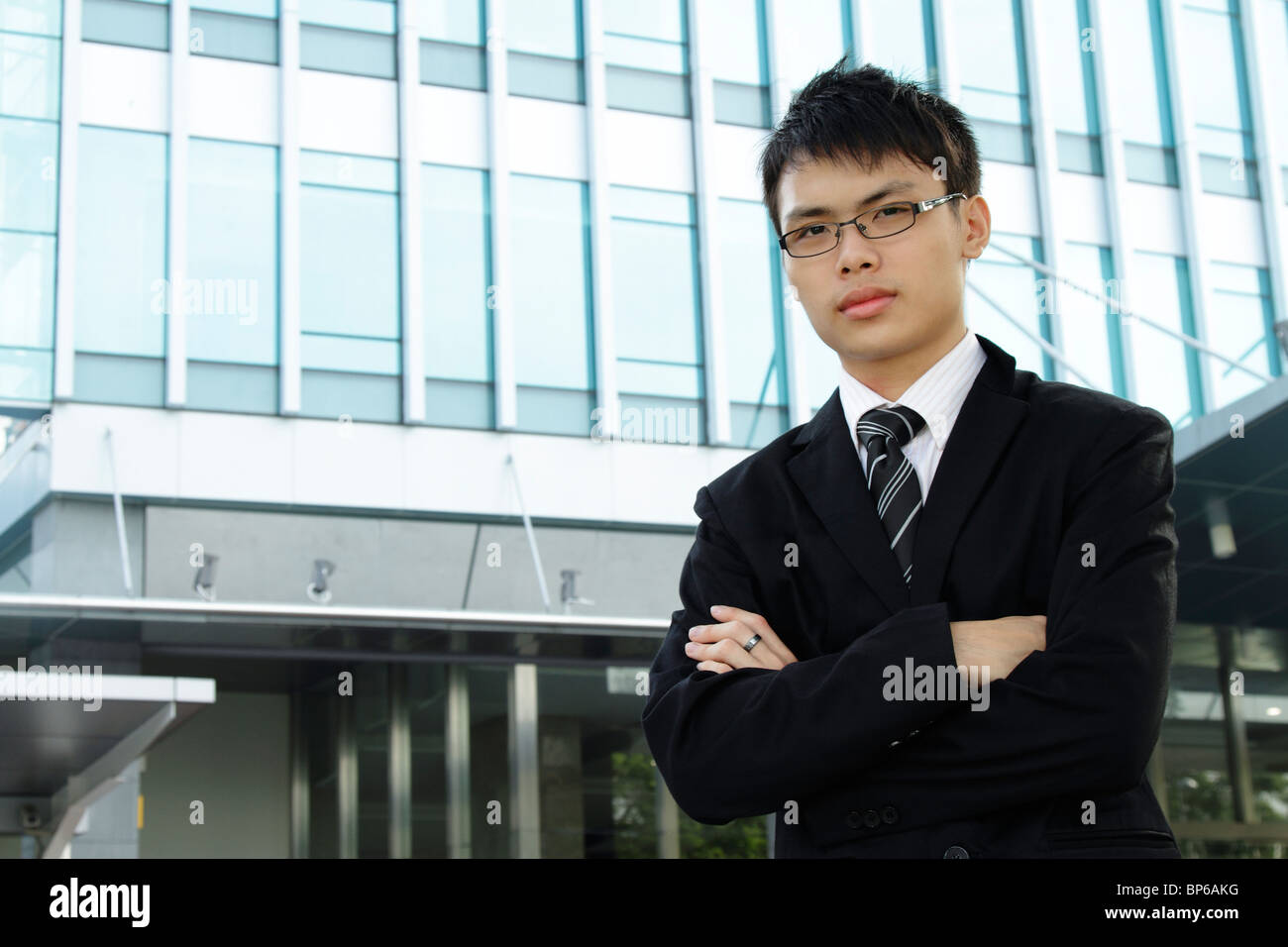 Un jeune chef d'entreprise asiatique debout devant un immeuble de bureaux Banque D'Images