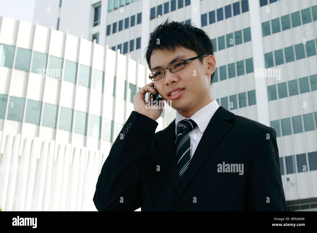 Un jeune chef d'entreprise asiatique parlant sur un téléphone cellulaire Banque D'Images