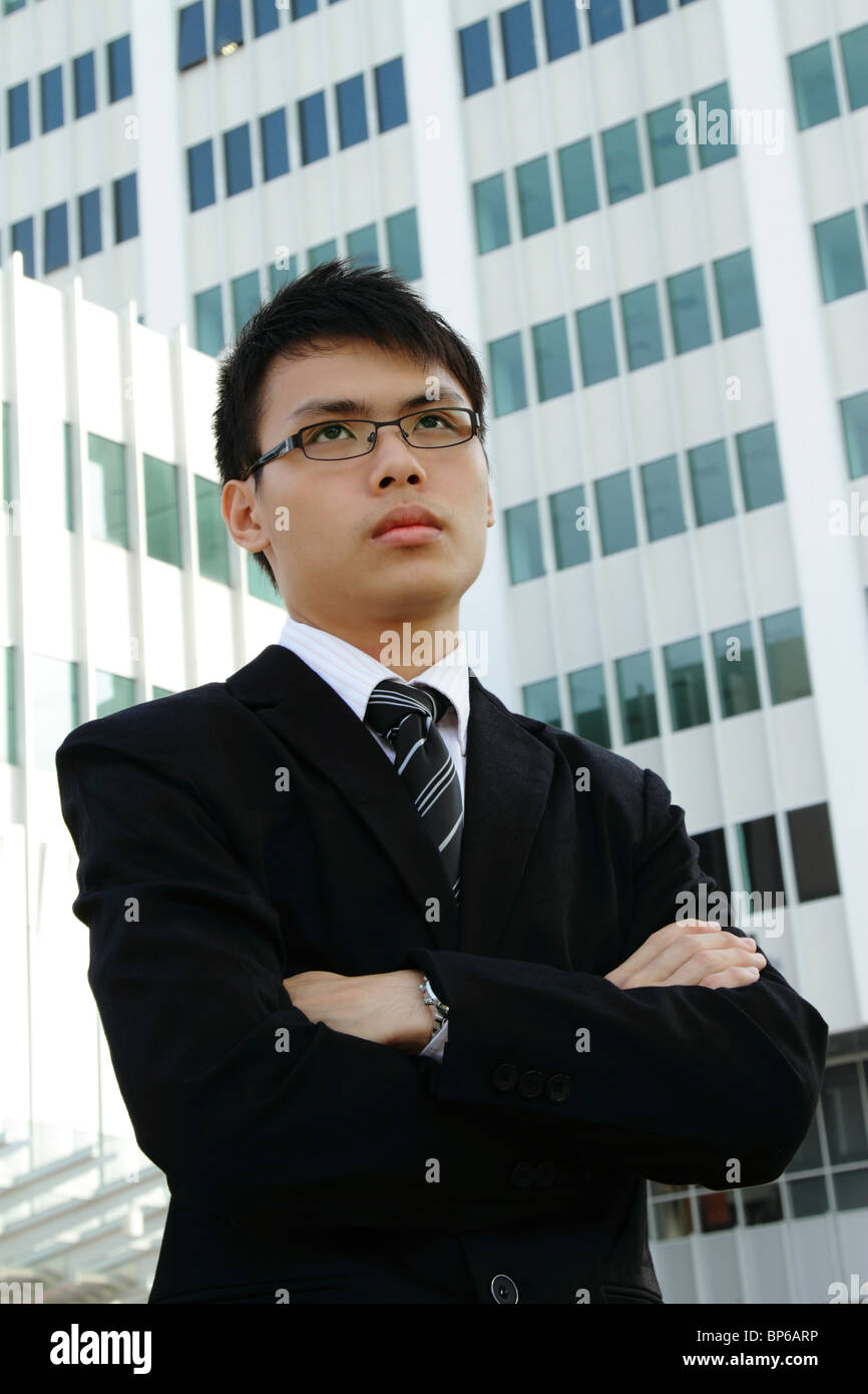 A Young Asian businessman standing in front d'un immeuble de bureaux Banque D'Images