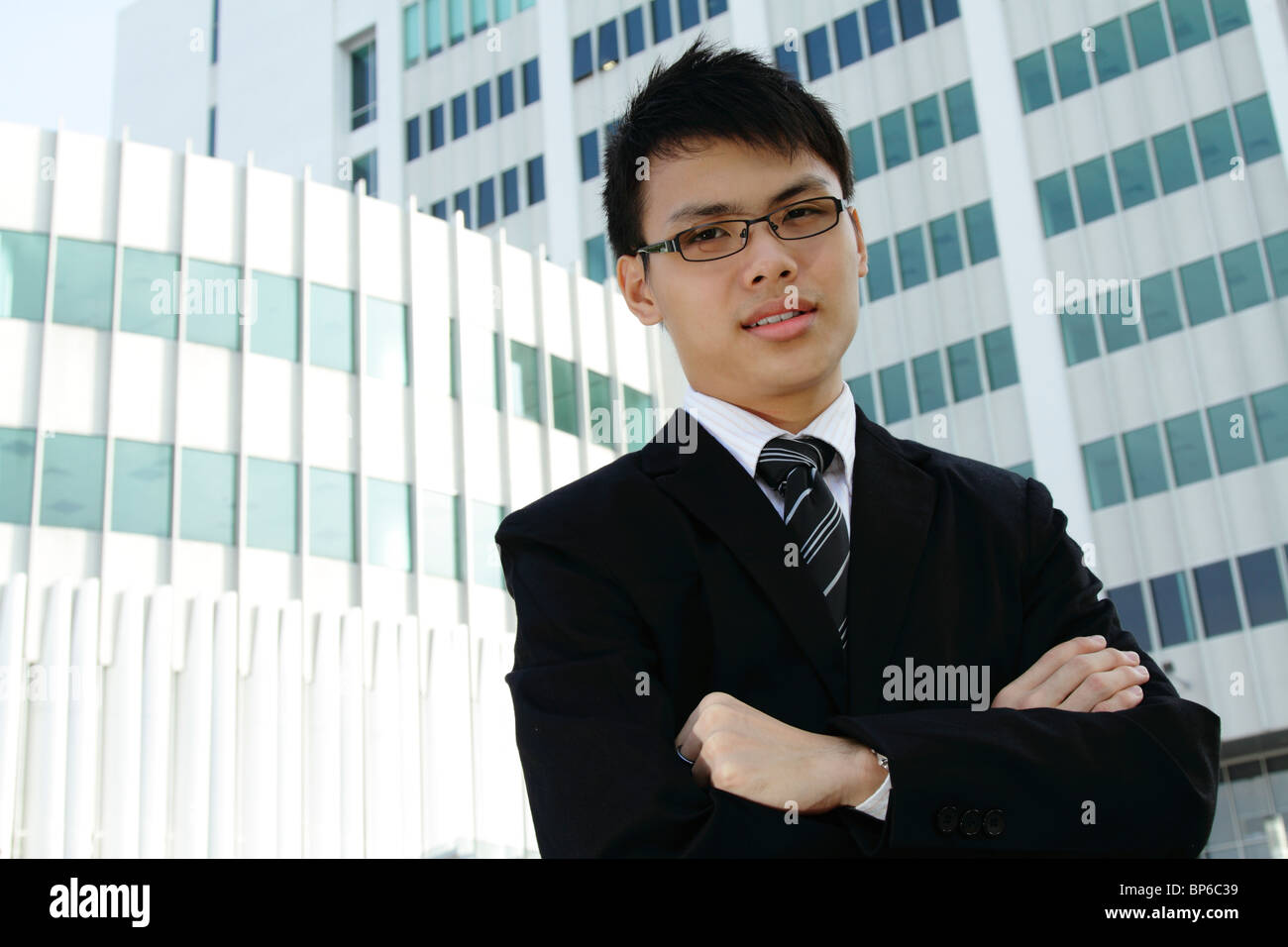 A Young Asian businessman standing in front d'un immeuble de bureaux Banque D'Images