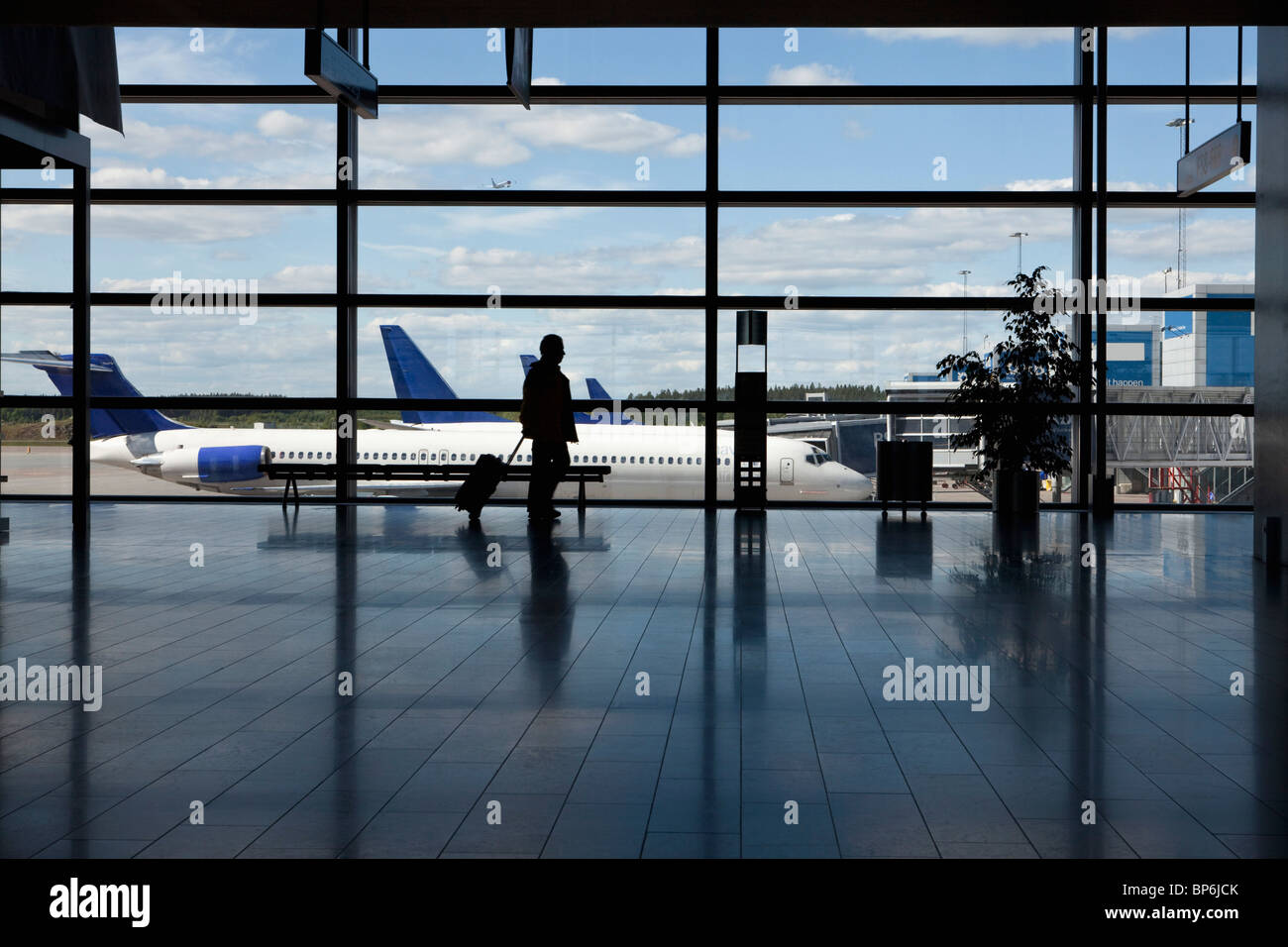 Un businessman walking par une fenêtre d'un aéroport, silhouette Banque D'Images