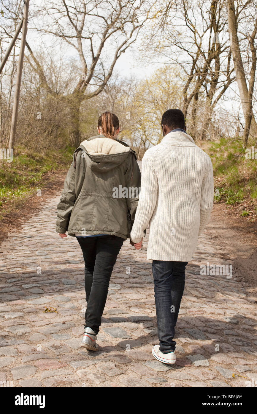Un jeune couple marchant sur une route pavée rural Banque D'Images