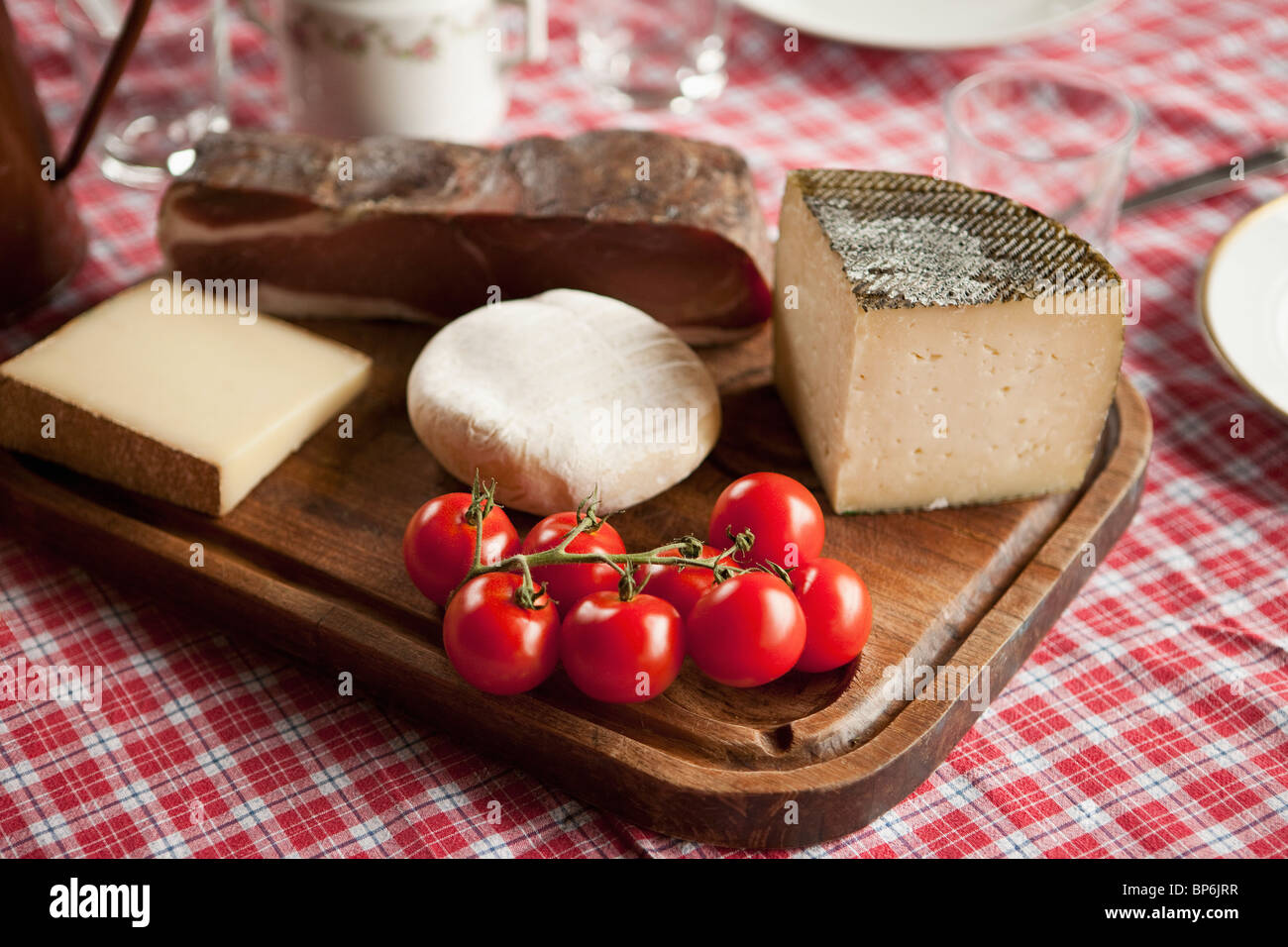 Le fromage, les tomates et le jambon de montagne sur une planche à découper en bois Banque D'Images