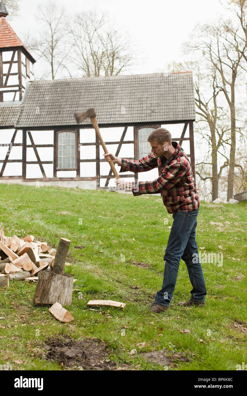 Un homme coupe du bois dans un cadre rural Banque D'Images