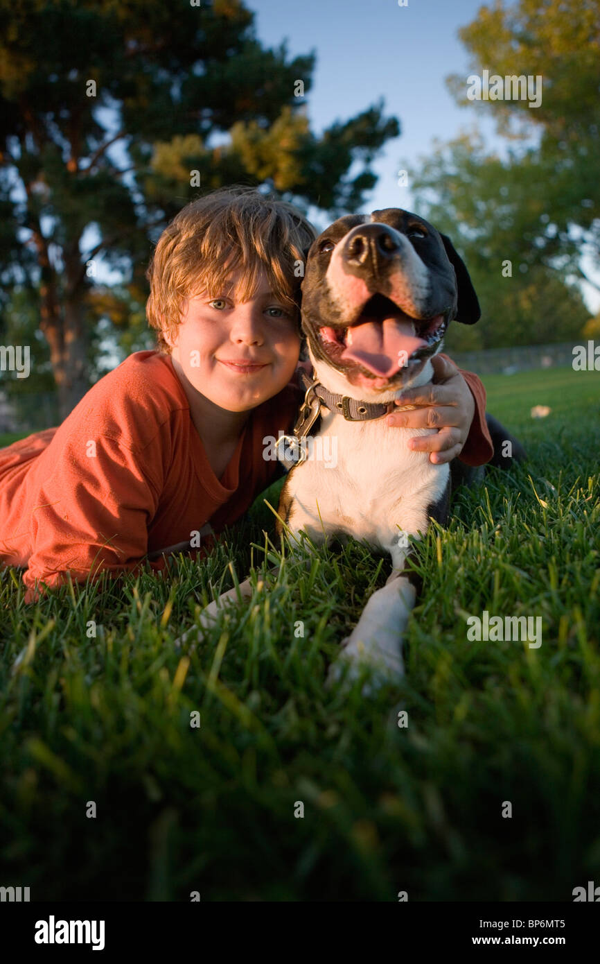 Portrait of a Boy lying on grass avec un chien Banque D'Images