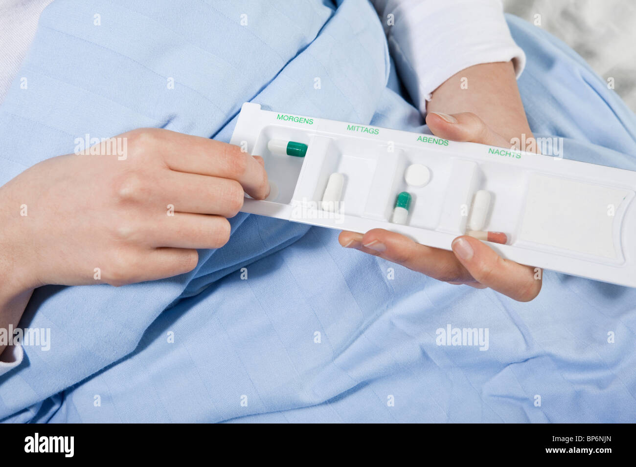 Un patient dans un lit d'hôpital à prendre une pilule d'un comprimé organisateur, se concentrer sur les mains Banque D'Images